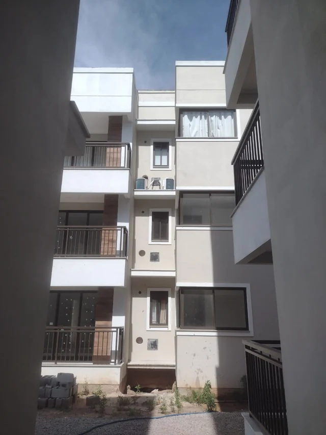 Vista entre edifícios de vários pavimentos com fachadas claras, janelas e sacadas com guarda-corpos.